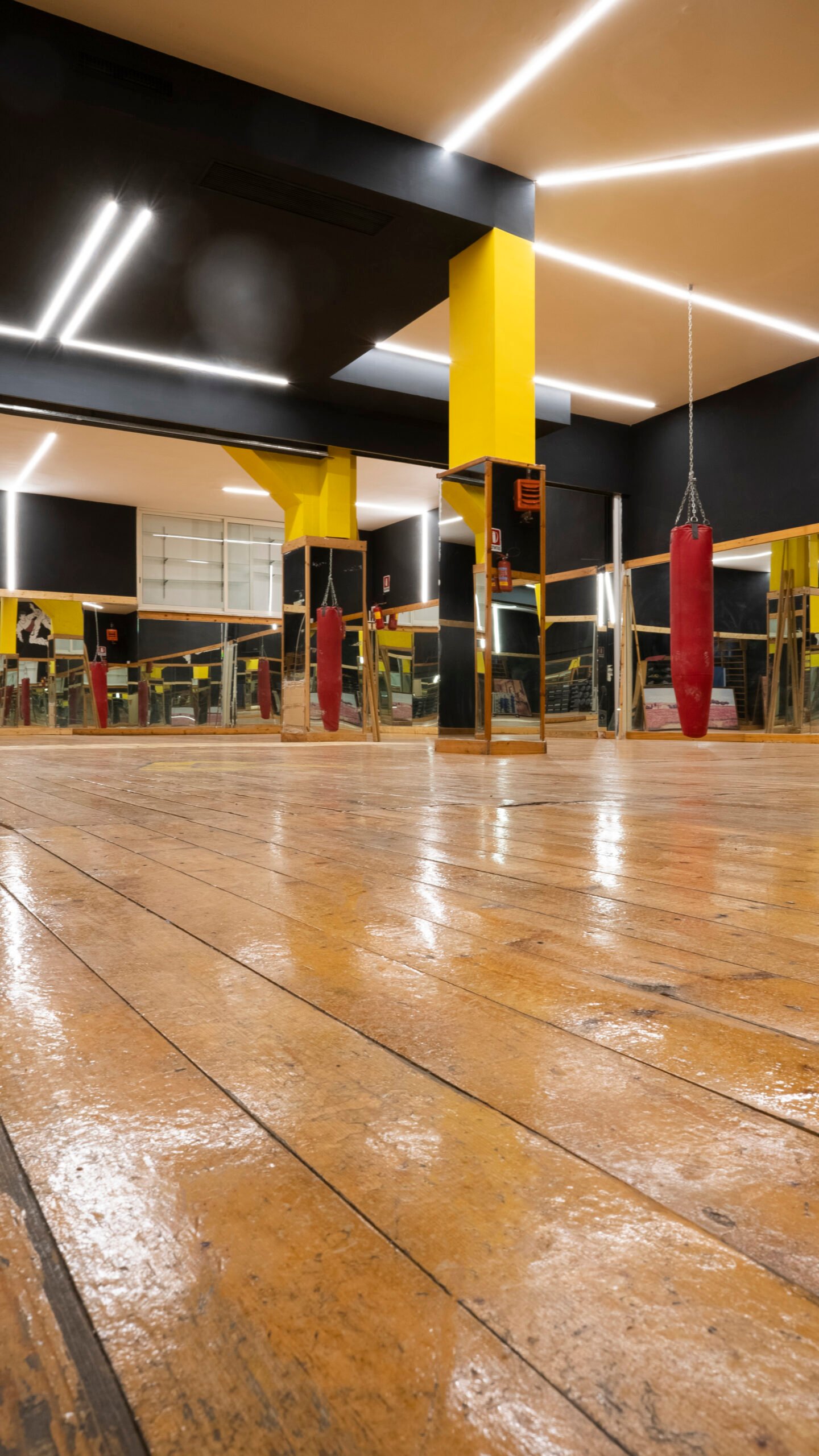La sala corsi di Athena Wellness, con specchi, colonne gialle e pavimento in legno